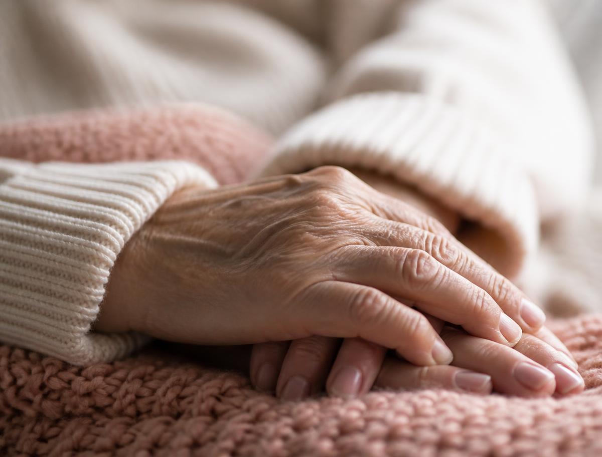 Two people's hands resting together on a soft blanket